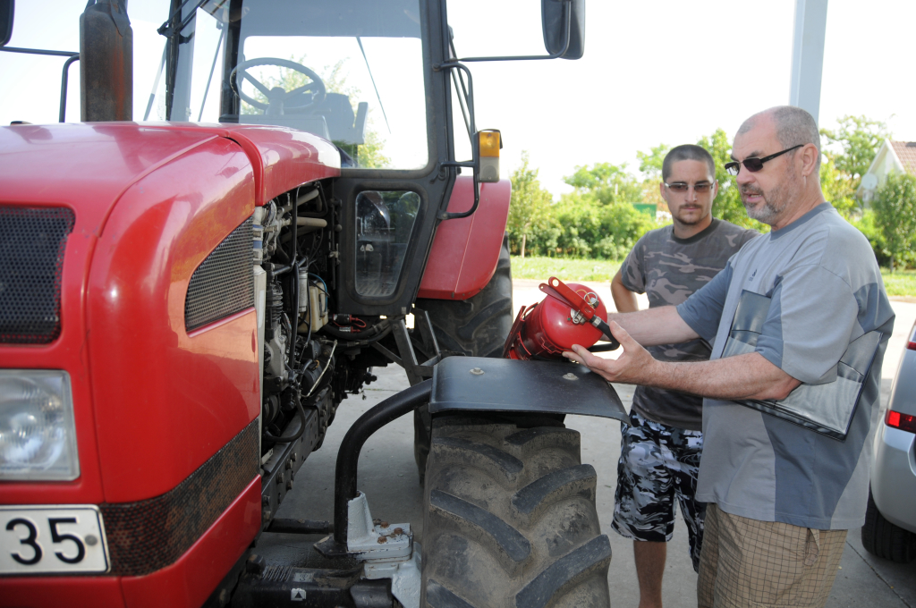 Csongrádi Pál éppen egy traktor tűzoltó készülékét ellenőrzi. Nem elég, ha ott van, működnie kell. (Fotó: Melega Krisztián)